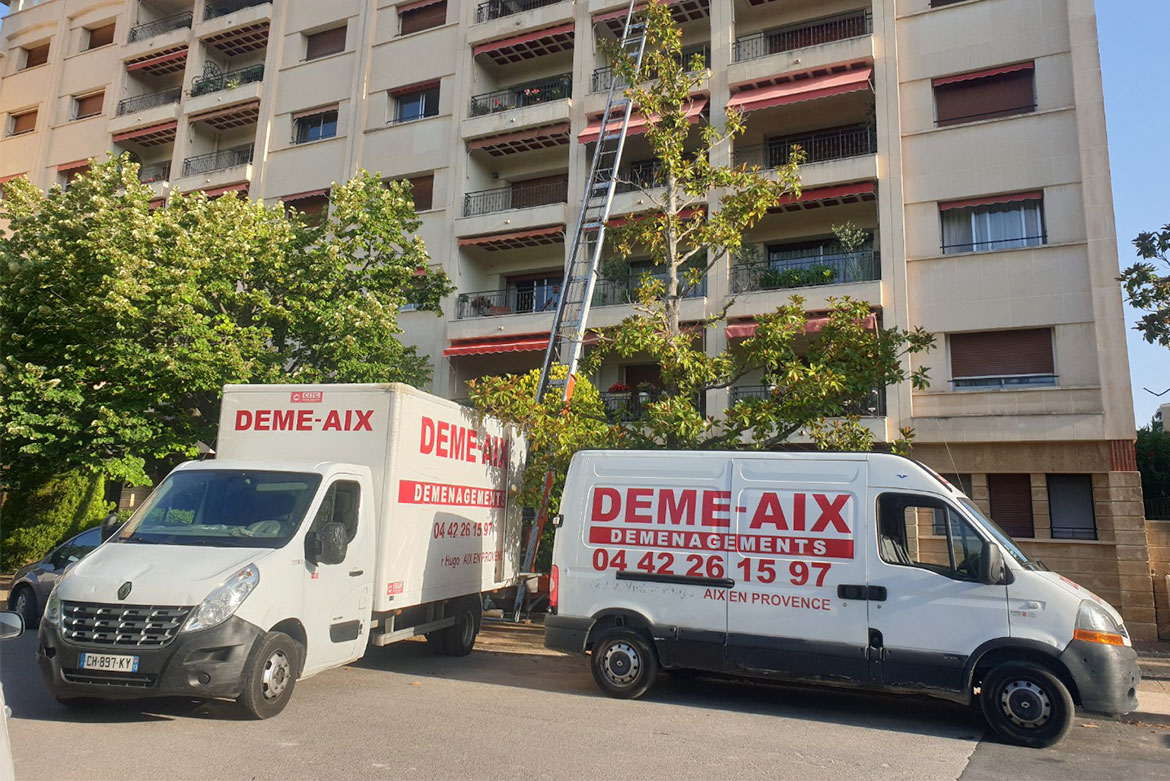 Véhicules de déménagement Démé-Aix stationnés devant un immeuble avec échelle élévatrice