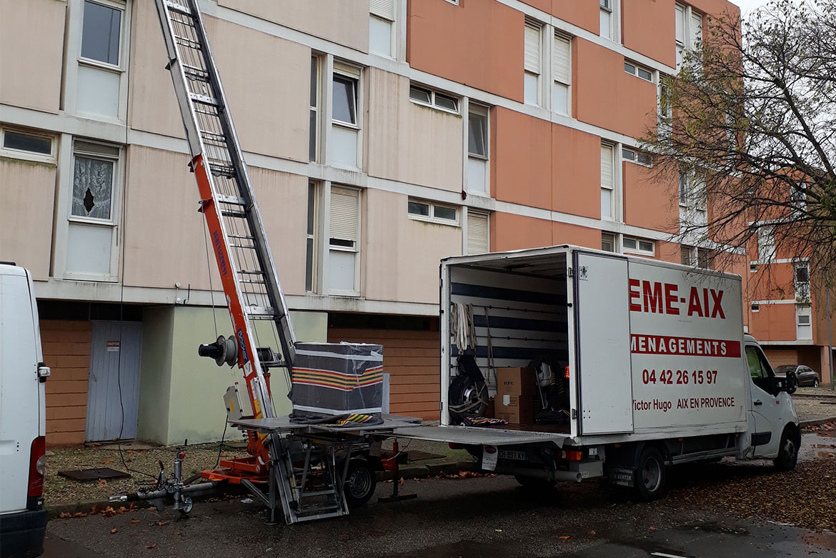 Camion de déménagement Démé-Aix avec monte-meuble devant un immeuble résidentiel
